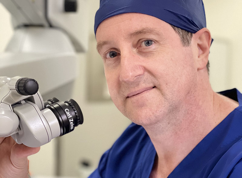 dr. neil cochrane looks through surgical microscope