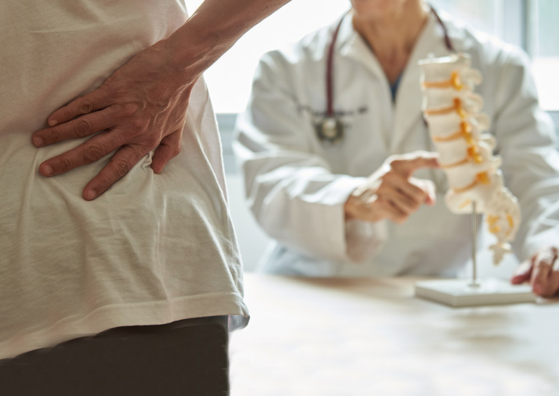 dr. neil cochrane points out lumbar spine to a patient